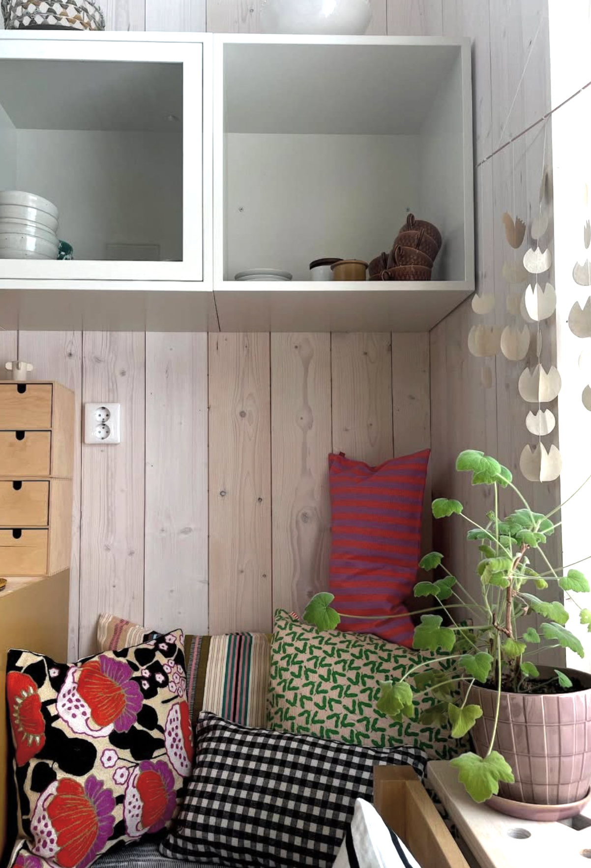 Nook with cushions and a plant against a wooden wall