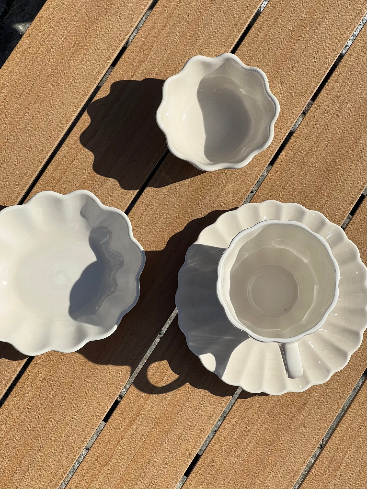 Three white ceramic dishes with scalloped edges on a wooden surface
