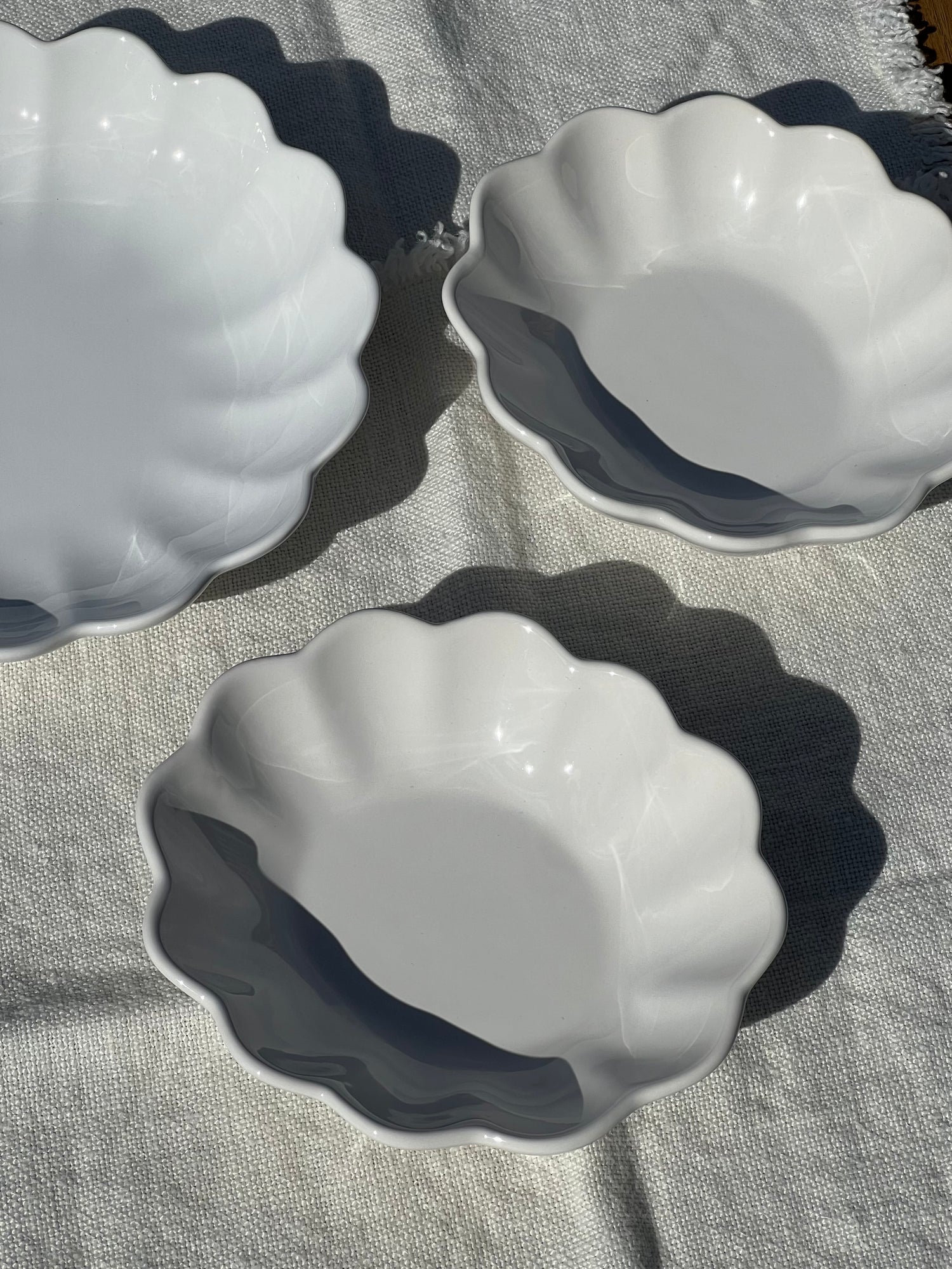Three white scalloped-edge bowls on a textured surface