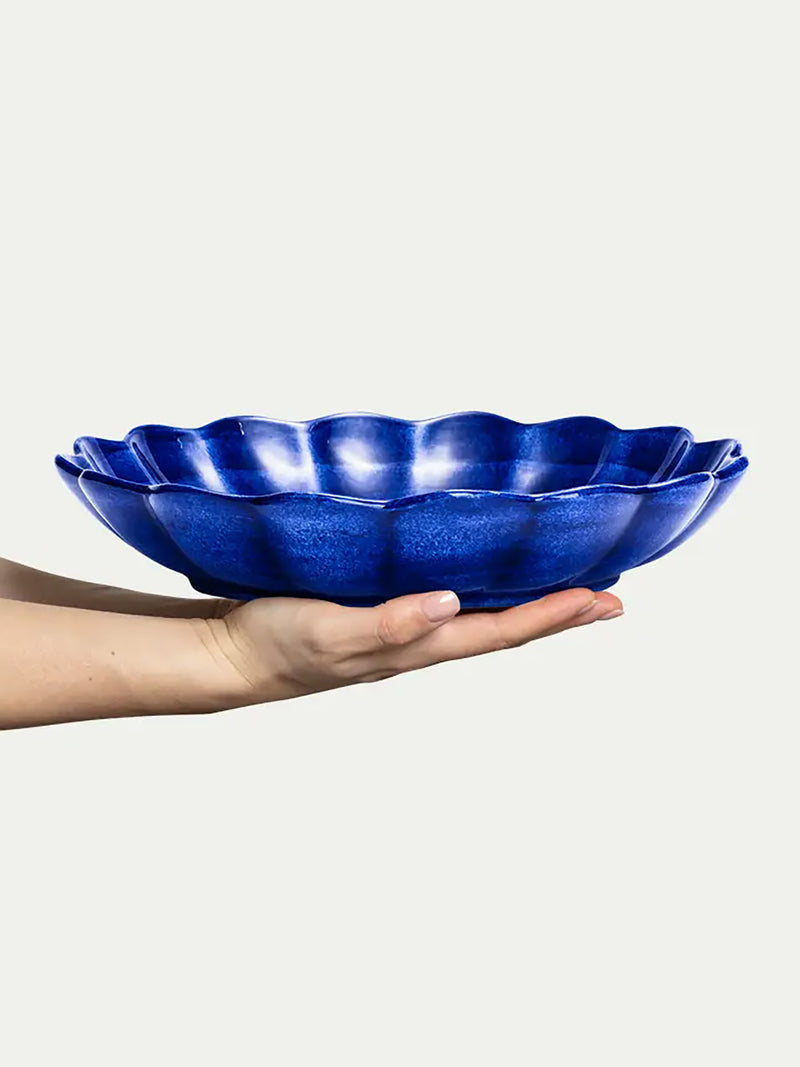 Hand holding a blue ceramic bowl against a white background