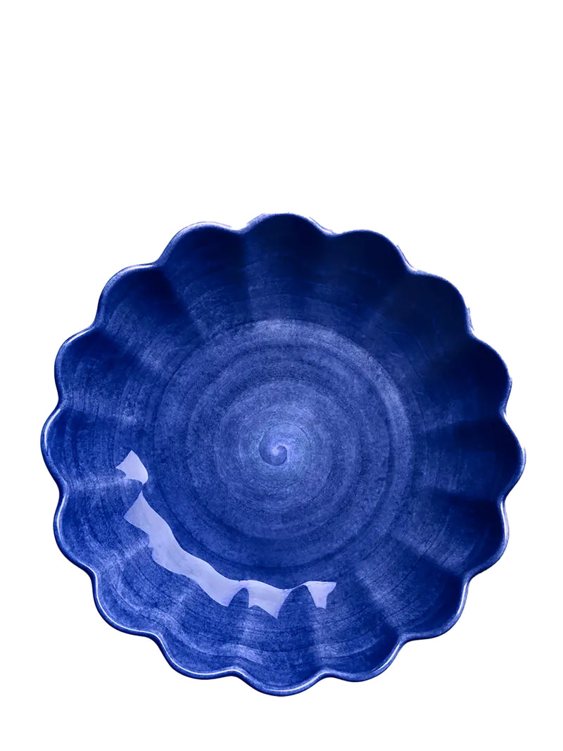 Blue ceramic bowl with scalloped edge on a white background