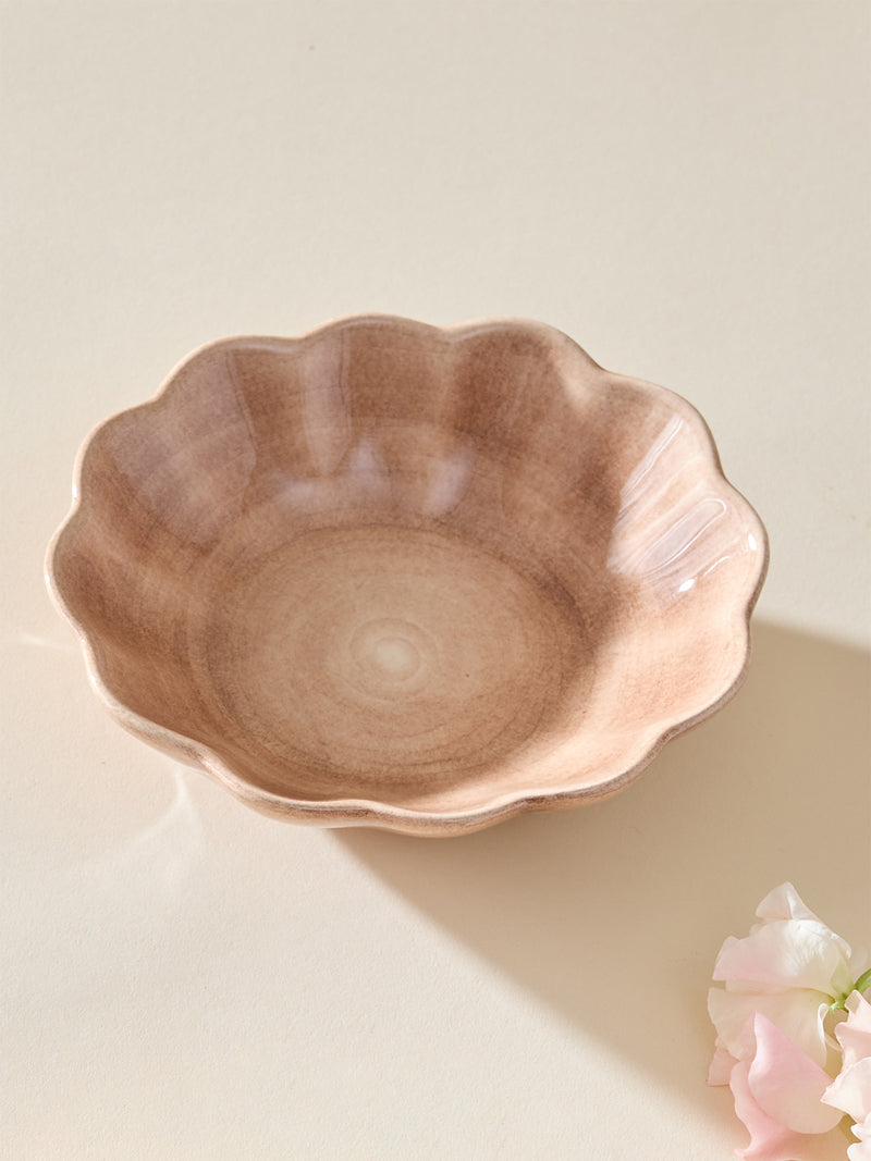 Decorative ceramic bowl with scalloped edge on a light background