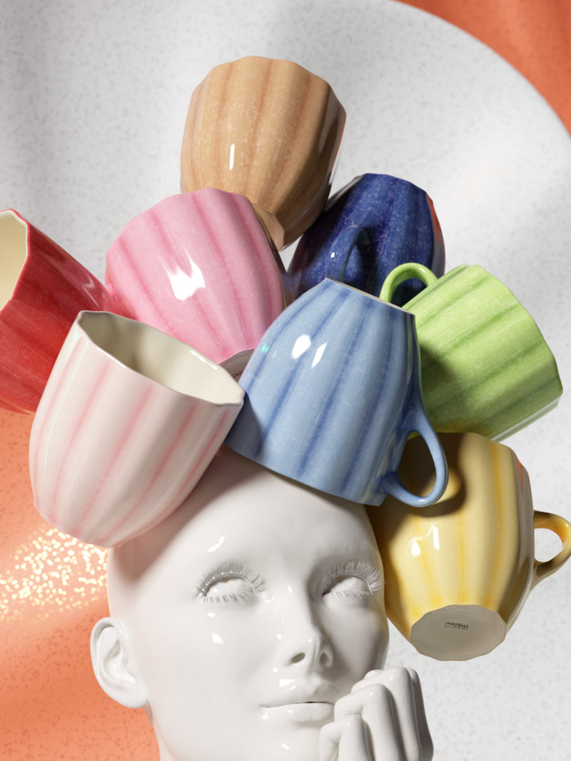 Colorful ceramic mugs stacked on a white ceramic face with a gradient background