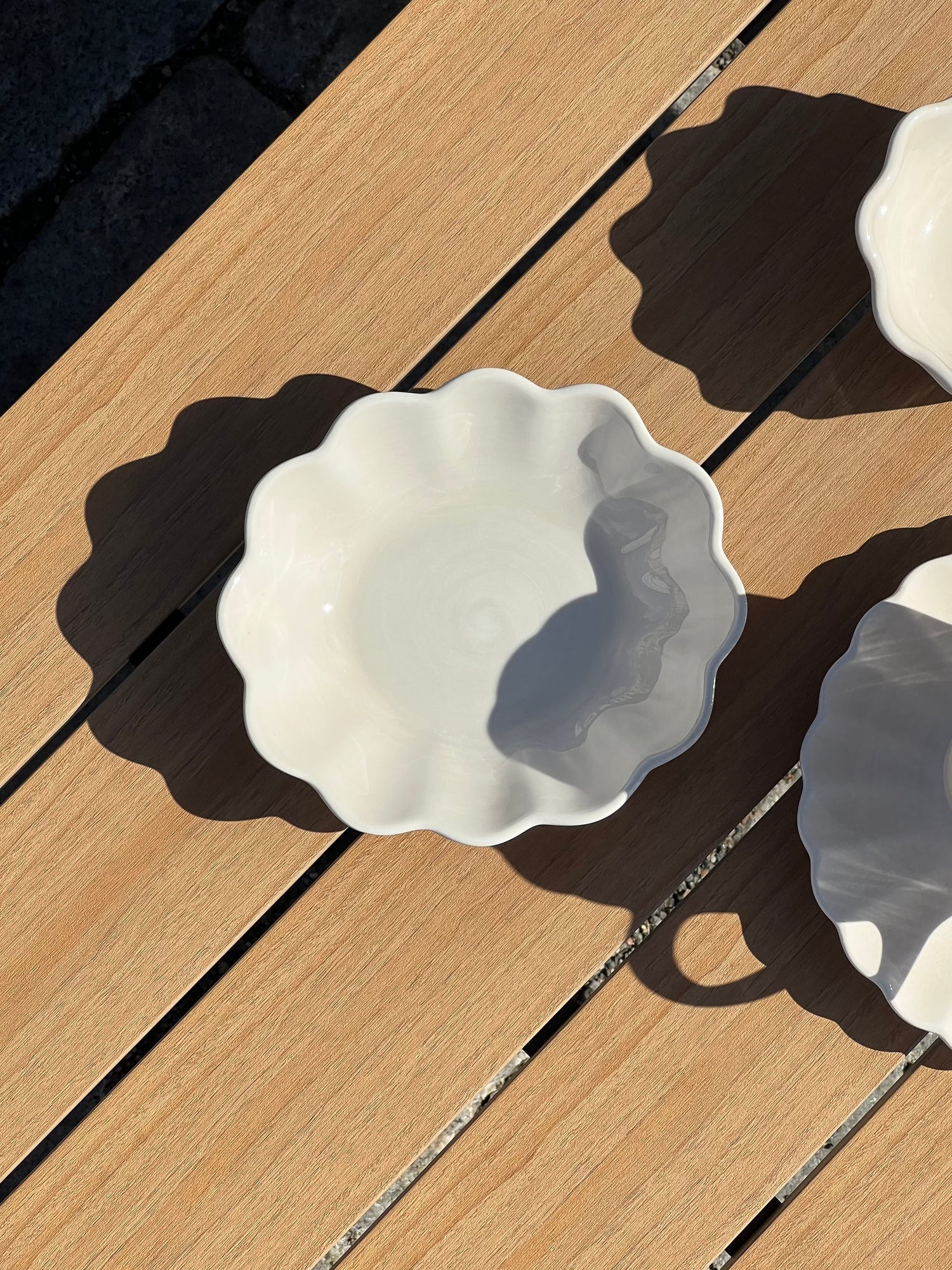 White ceramic dish with scalloped edge on a wooden surface