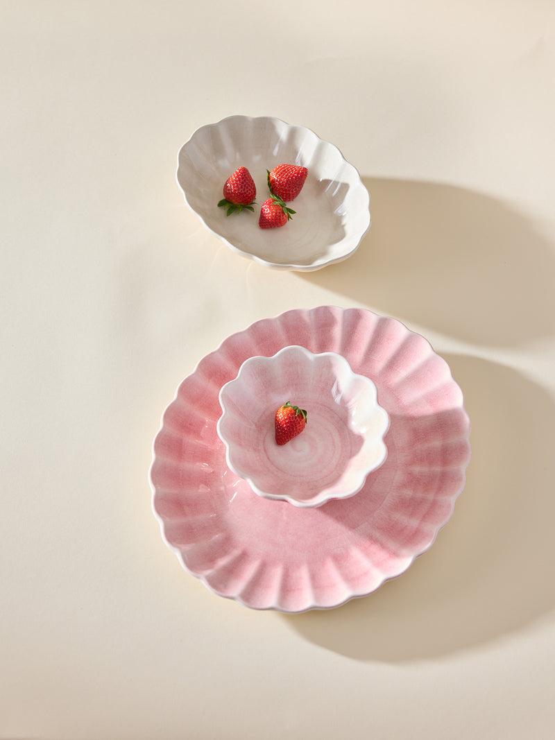 Light pink and snow white ceramic tableware with scalloped edges, 2 small oval bowls and one large oval plate, styled with strawberries on a warm beige background.