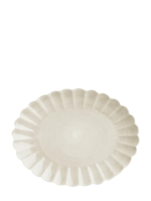Oval off-white ceramic plate with scalloped edge on a white background