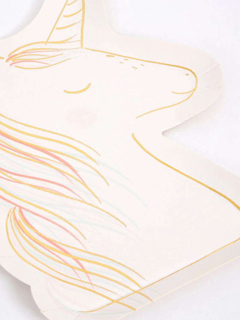 A close-up of a unicorn-shaped paper plate in warm off-white, decorated with gold line art and pastel pink, yellow, and blue hair details, shown on a white background.