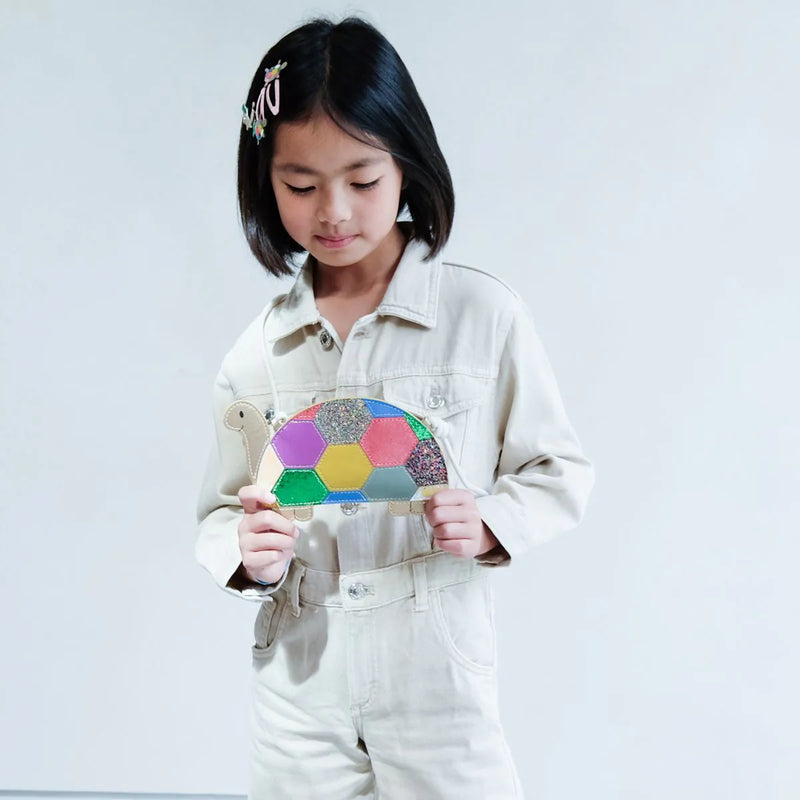 Child holding a colorful turtle handbag