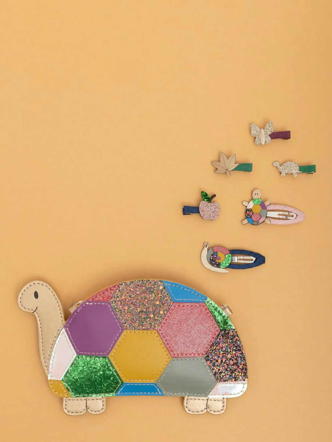 Colorful tortoise-shaped bag with decorative hair clips on a beige background