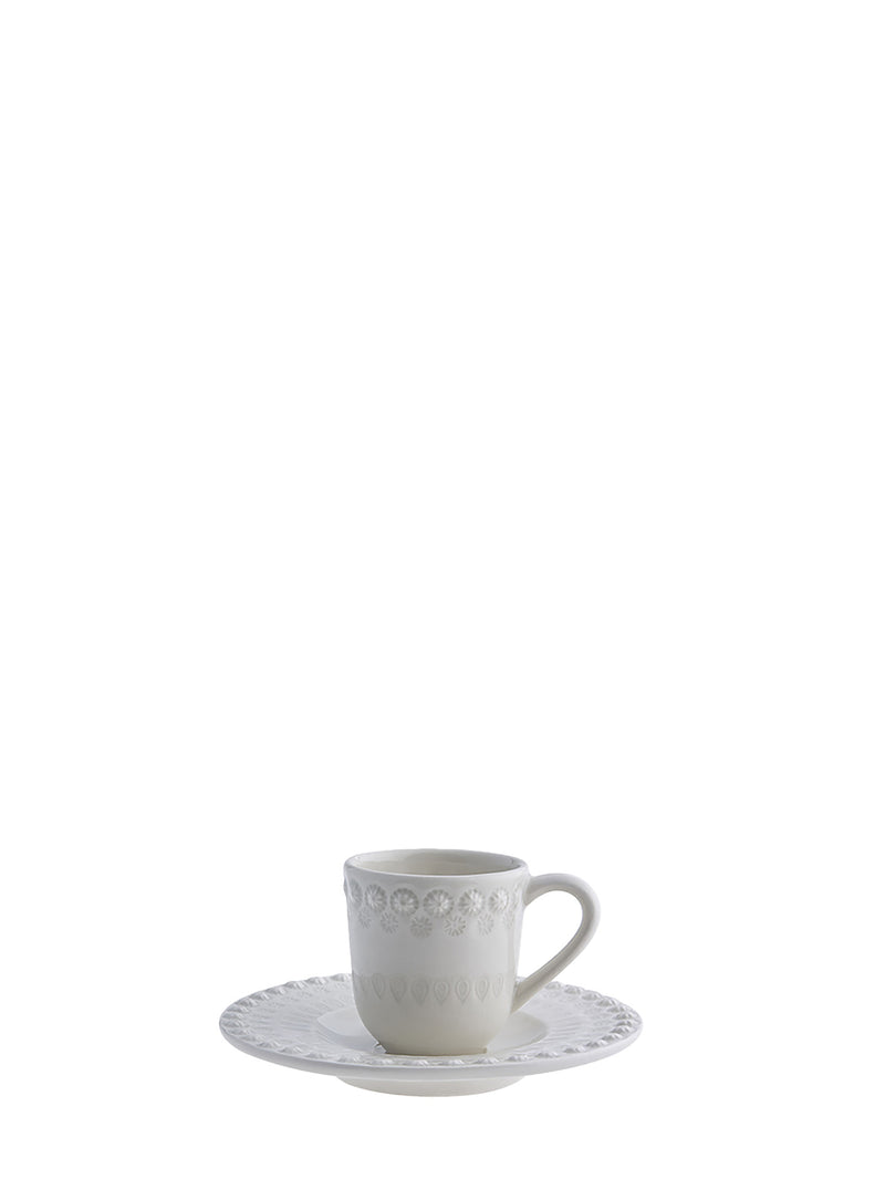 White ceramic cup and saucer with decorative patterns on a white background