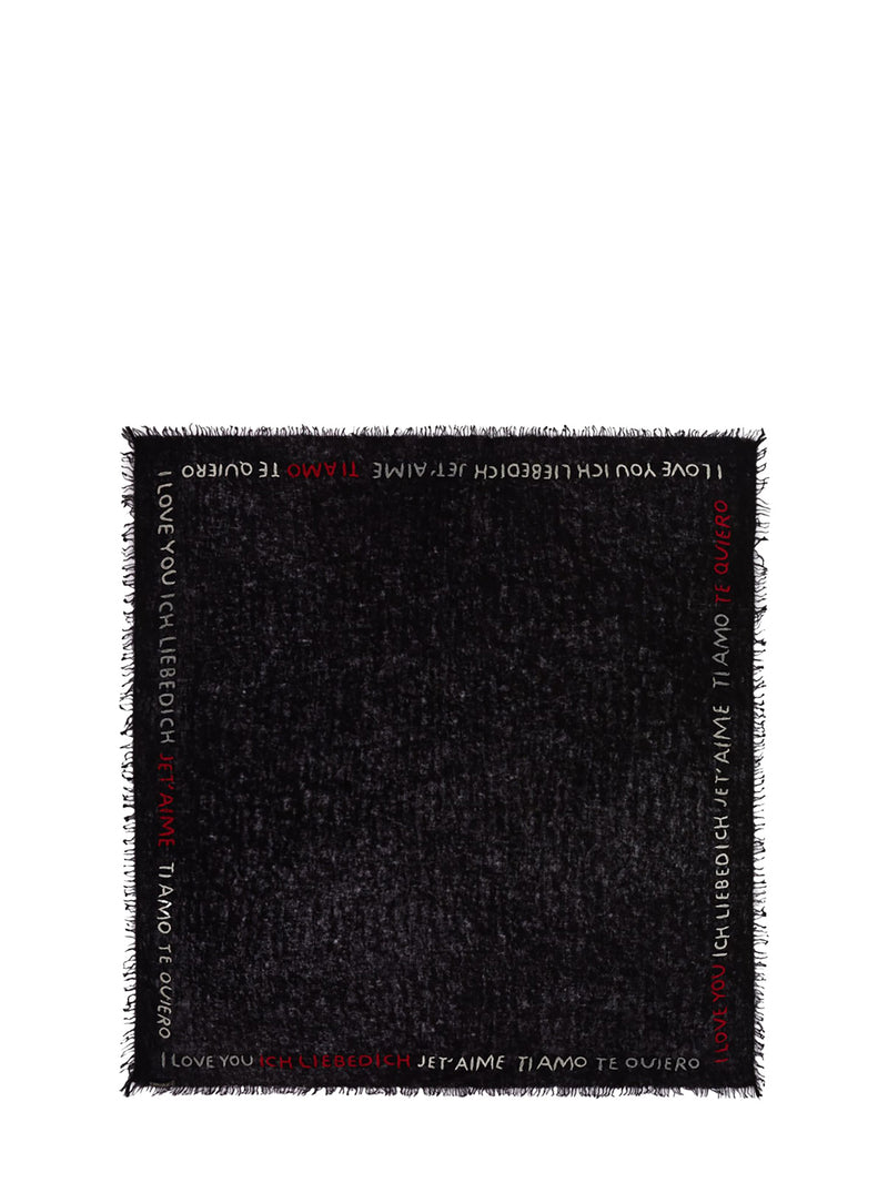 A black woven throw blanket with fringe edges, featuring white and red text printed along the borders.