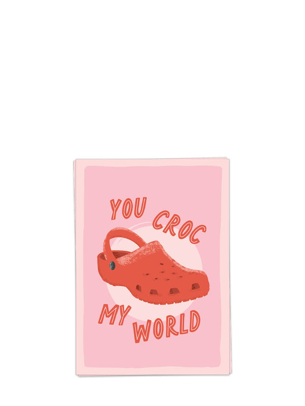 A greeting card with an image of red croc shoe and text 'You Croc My World' on a white background
