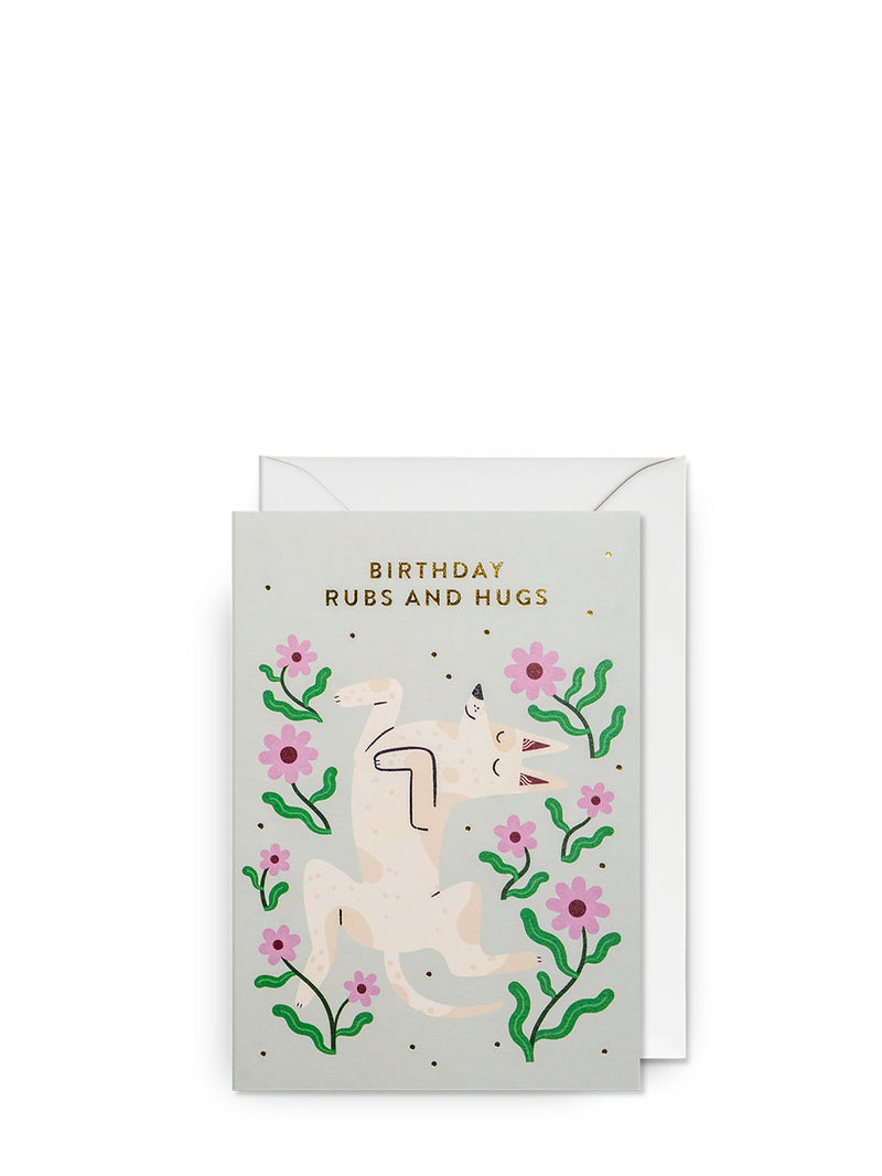 Birthday greeting card with an  illustration of smiling dog laying on a meadow and floral elements on a pale grey background with a white envelope.