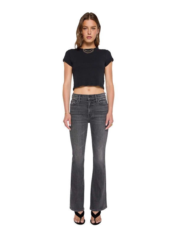 Woman wearing a black crop top and gray flared Mother jeans on a white background