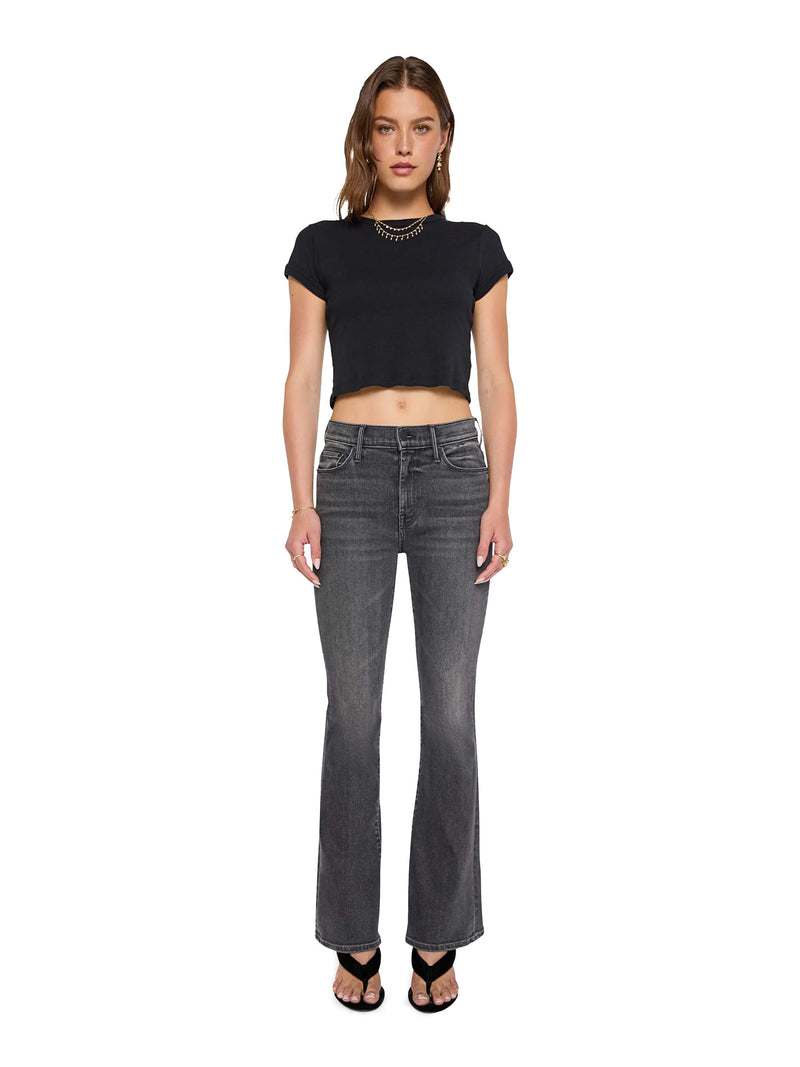 Woman wearing a black crop top and gray flared Mother jeans on a white background