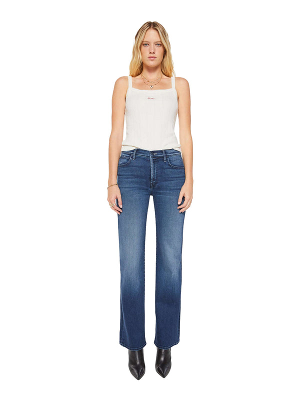 A woman modeling a pair of medium-wash blue jeans with a faded gradient effect towards the hem, paired with a white tank top and black pointed-toe heels, shot against a solid white background.