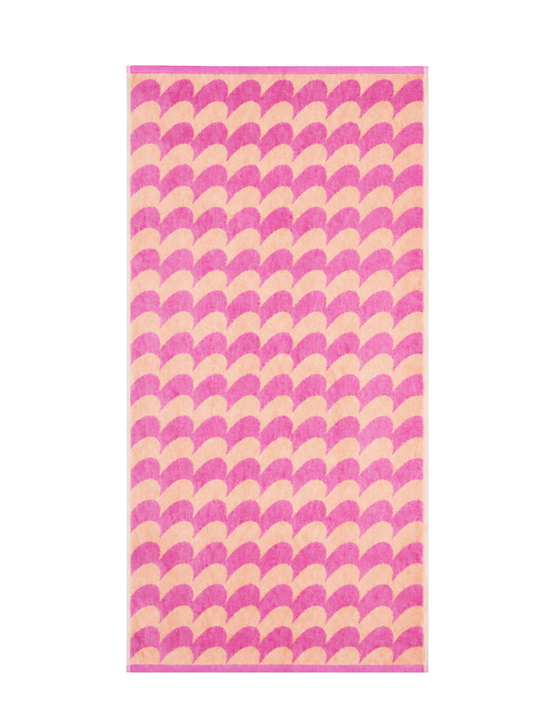 A rectangular 140 x 70 cm sized bath towel featuring a repeating curvy mountain row o or fan pattern in alternating shades of pink and light peach on a white background.