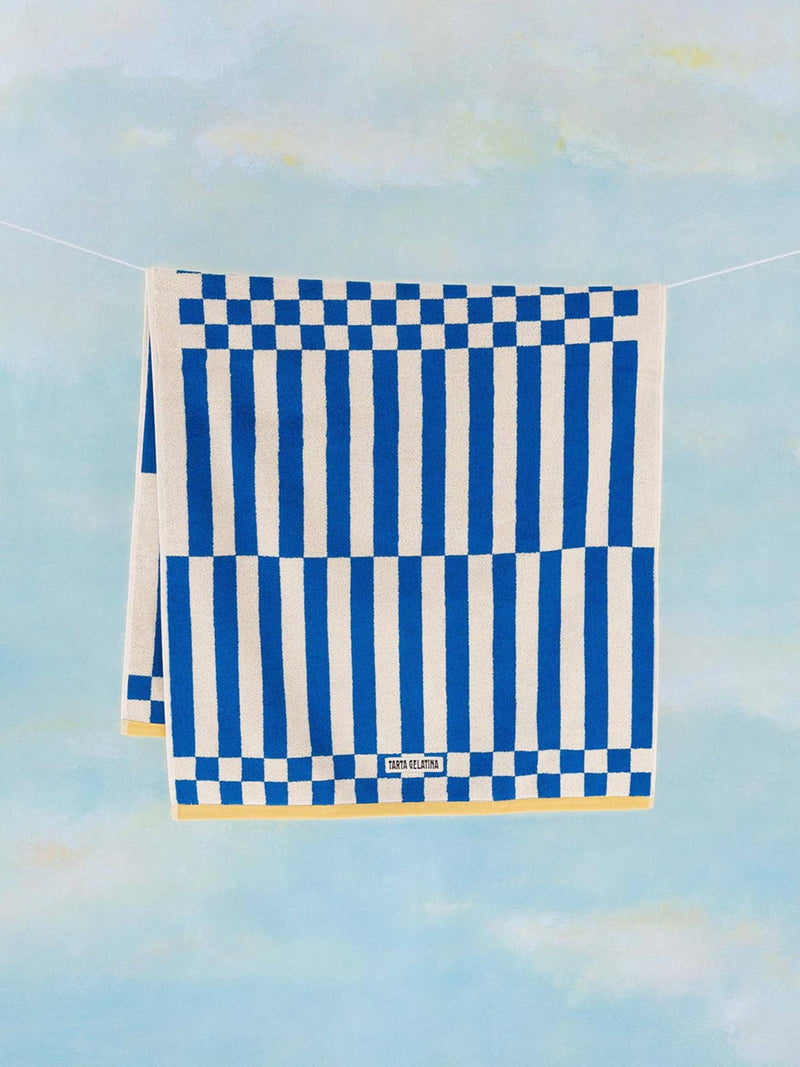 Indigo blue and off-white checkered beach towel hanging on drying line photographed against a sky blue background