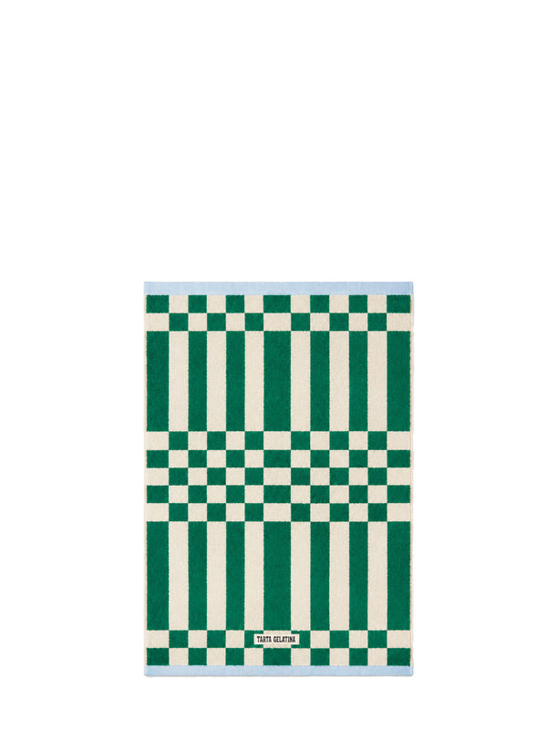A rectangular terry hand towel with a geometric pattern of green and off-white vertical stripes and checkerboard sections, and a light blue border, shown on a plain white background.
