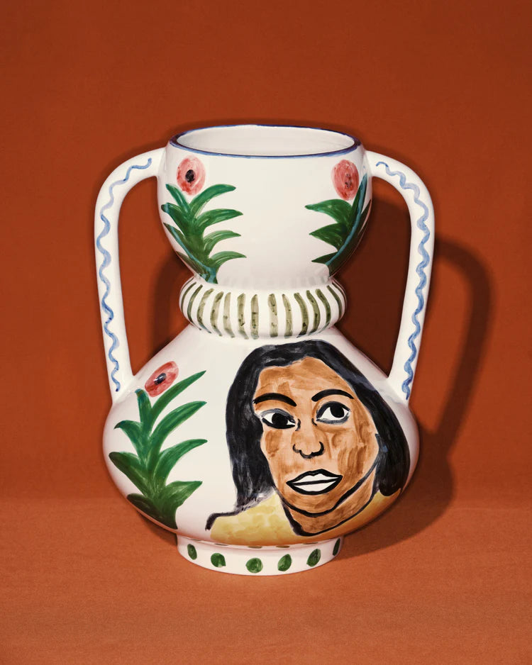 Ceramic vase with floral design and face painting on an orange background