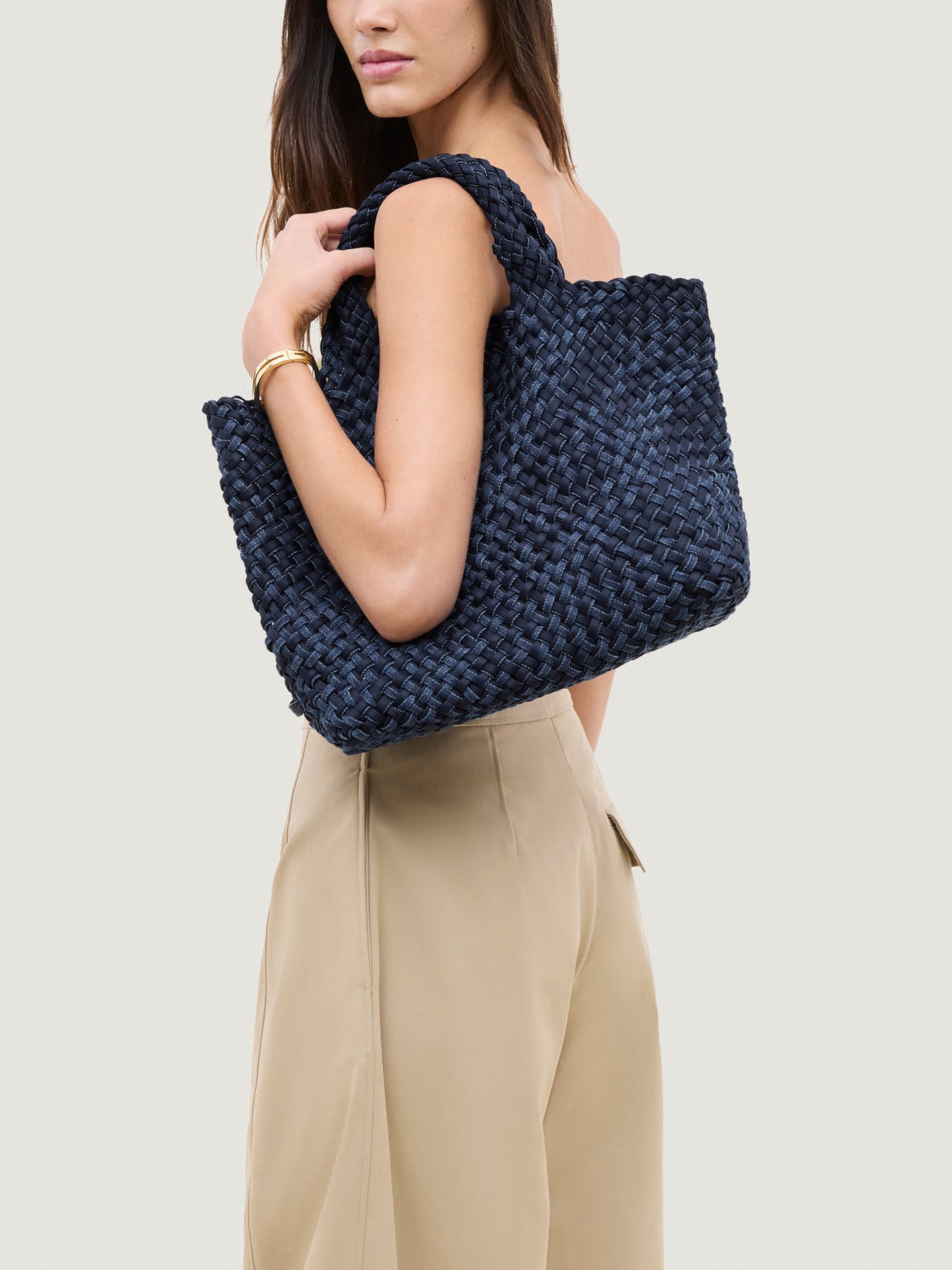 Woman holding a navy blue woven handbag by Naghedi