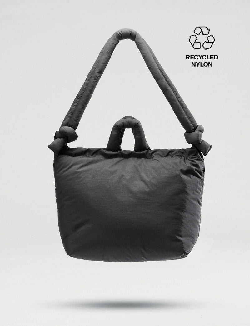 Black soft tote bag with recycled nylon label on a light gray background