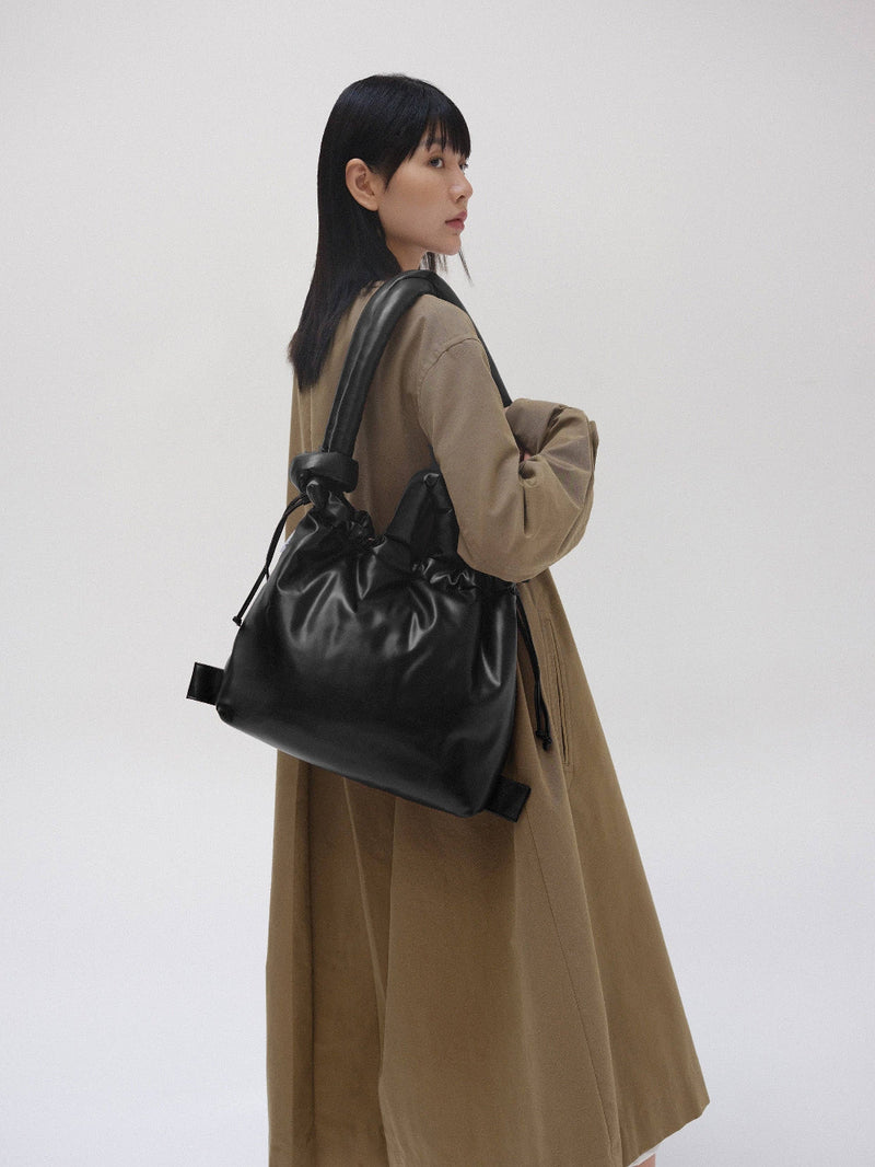 Woman wearing a black leather backpack on her shoulder against a white background