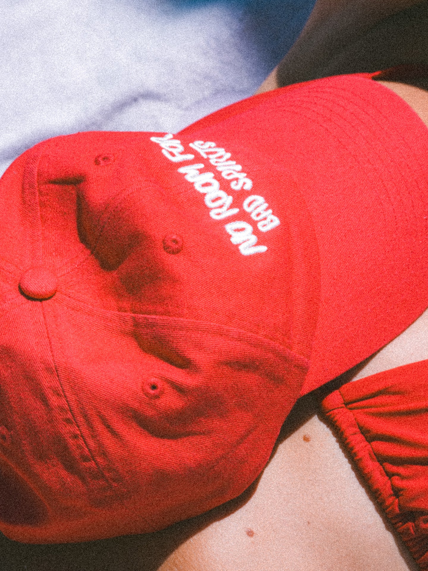 Red cap with white text worn by a person, close-up view.