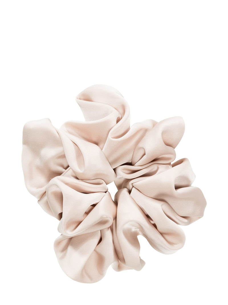 A single scrunchie in warm ivory satin with a tiniest of pink hue, photographed from directly above on a seamless white background.