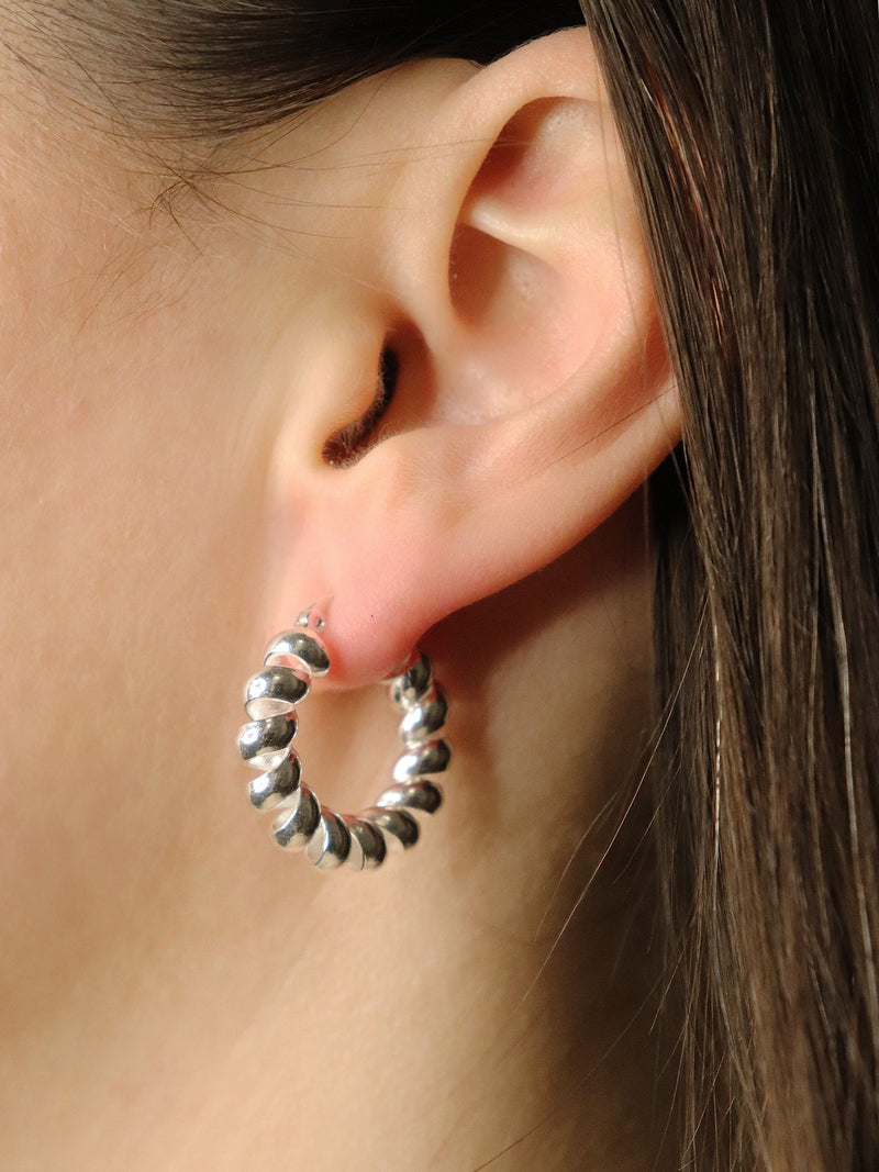 Silver hoop earrings worn by a person with brown hair.