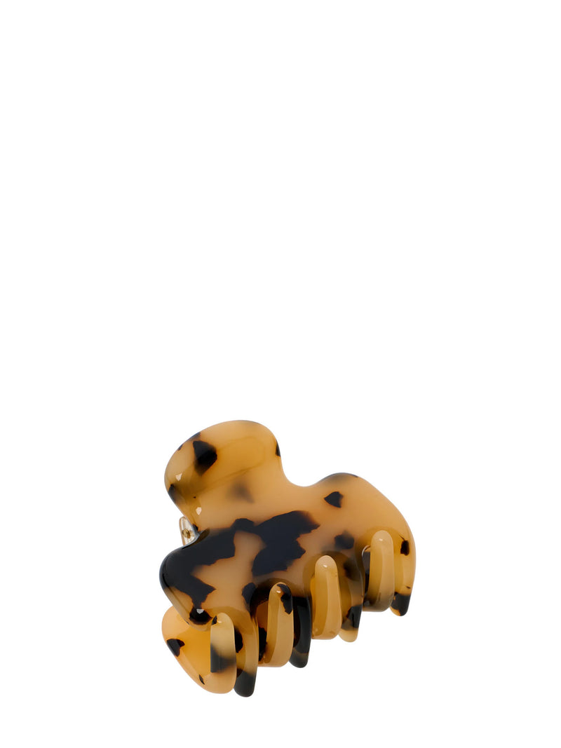 A tortoiseshell hair claw clip with a translucent amber-brown base and black mottled spots, shown on a plain white background.