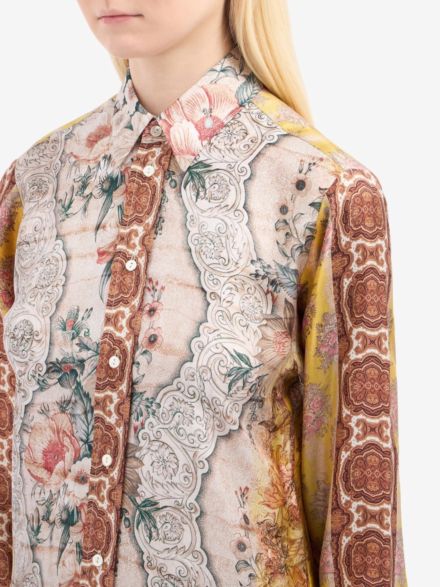 Close-up of a person wearing a patterned shirt with floral and paisley designs.