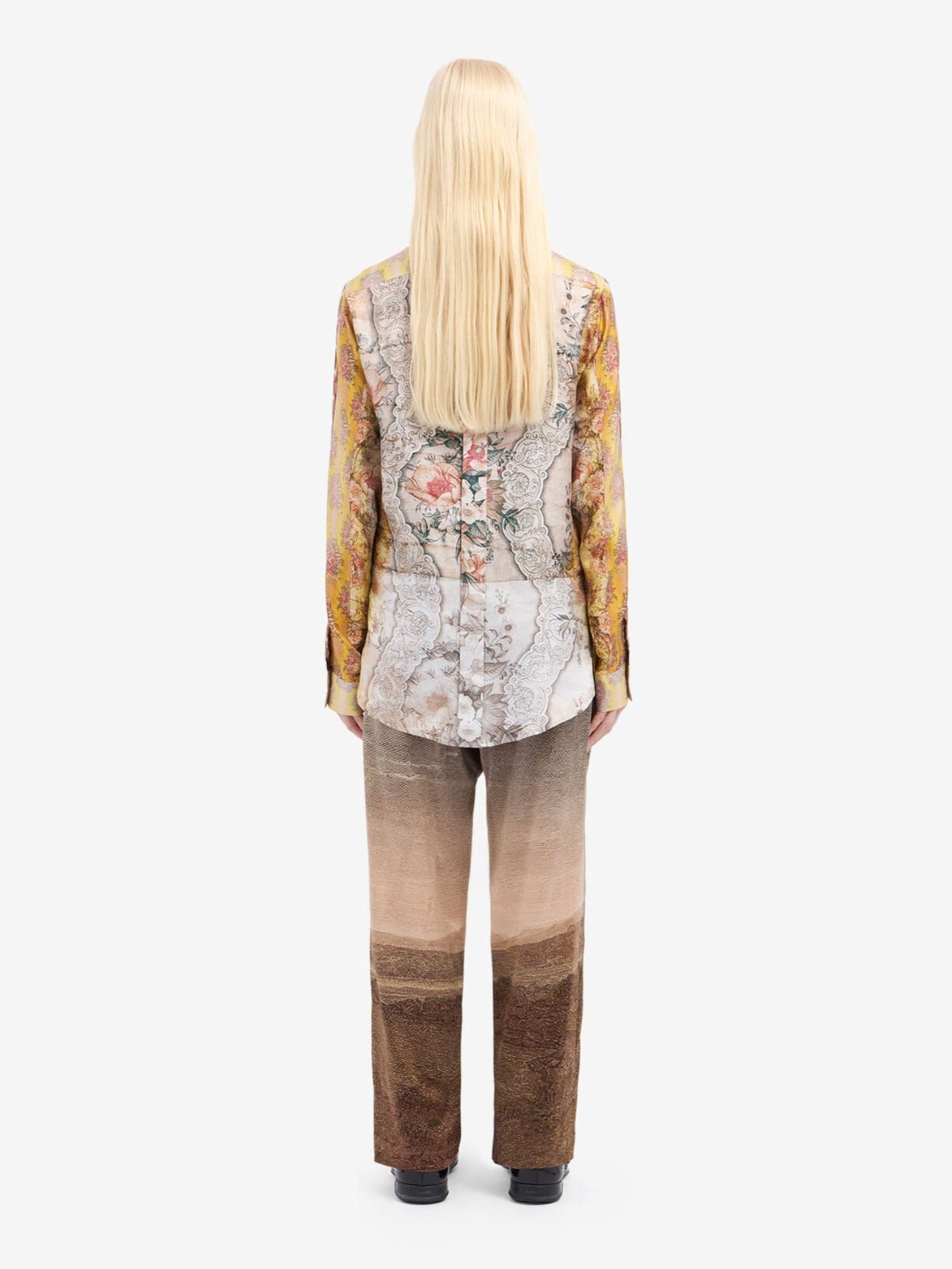 Person wearing a patterned top and pants on a white background