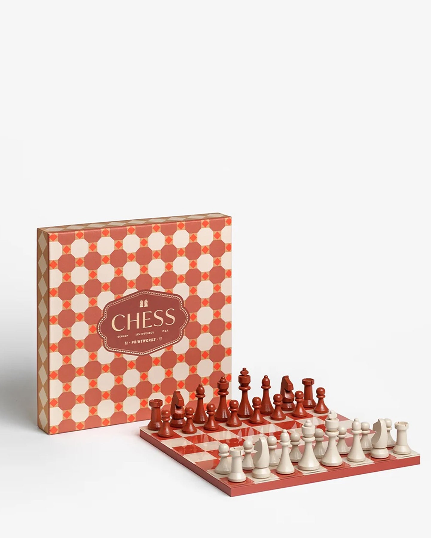 A wooden chess set with a red and cream checkered board, red and cream chess pieces, and a decorative patterned storage box on a clean white background.