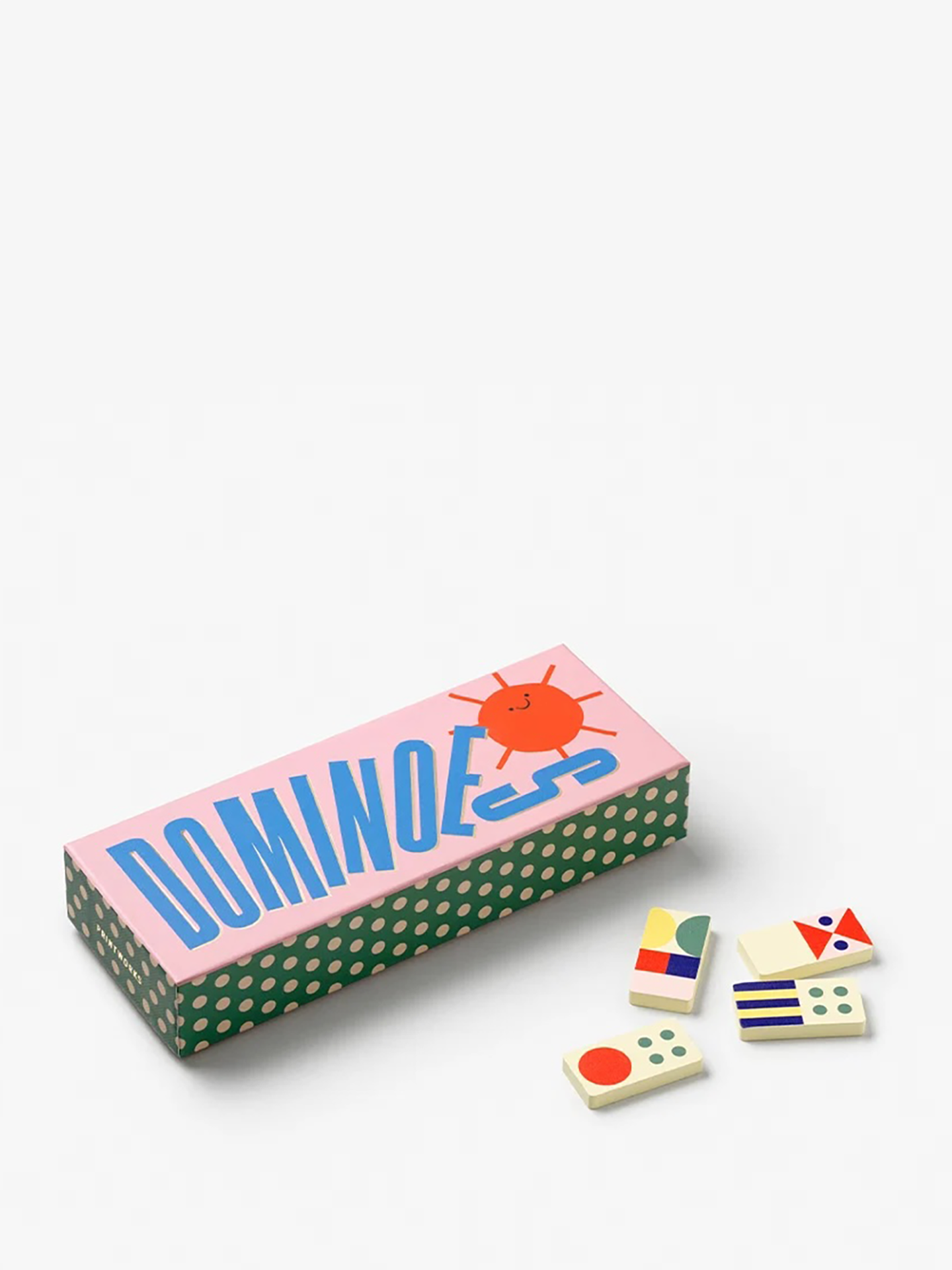 A boxed game set labeled DOMINOES with a pink lid, green-and-white polka-dotted sides, and several small domino tiles placed beside it on a clean white background.