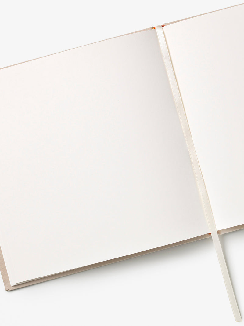 Rectangular notebook with blank pages and cream white satin ribbon bookmark open on a white background