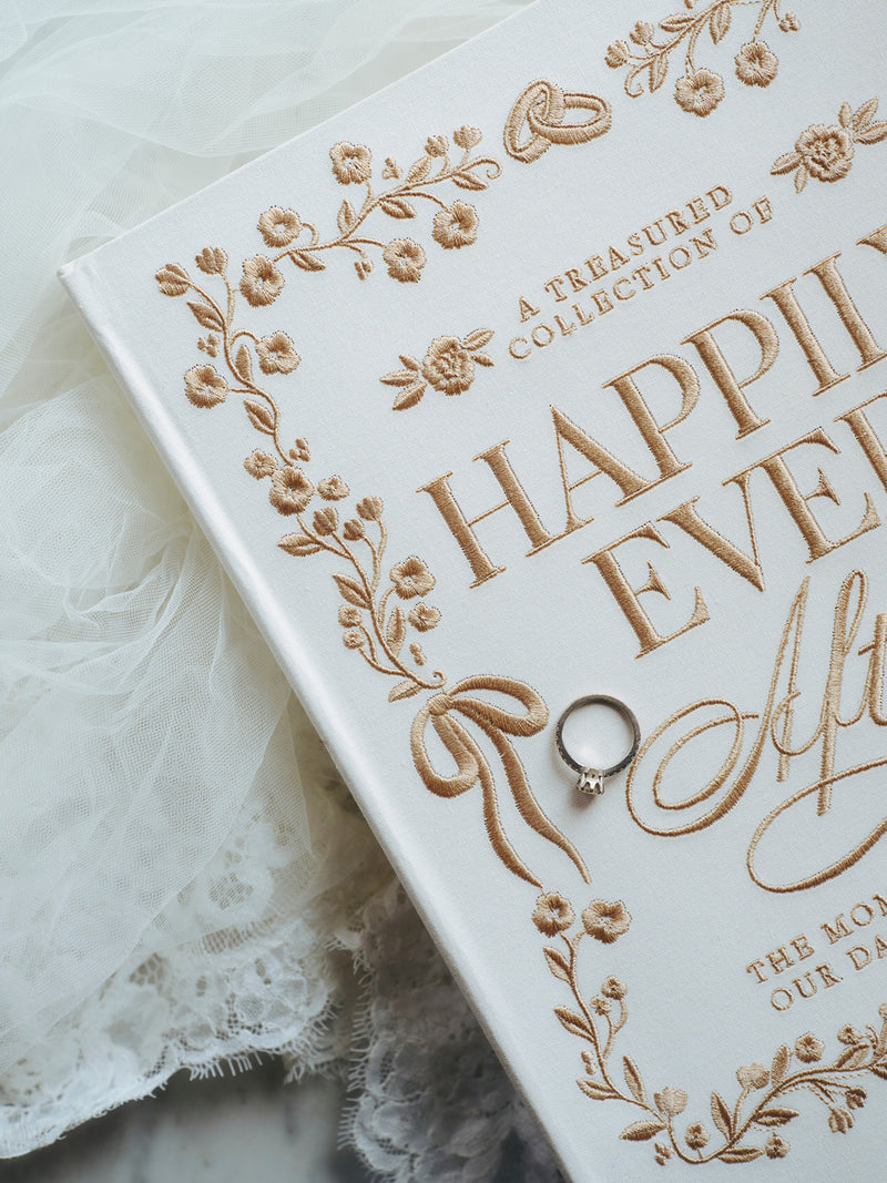 Decorative photo album titled 'Happily Ever After' with wedding ring on a lace background