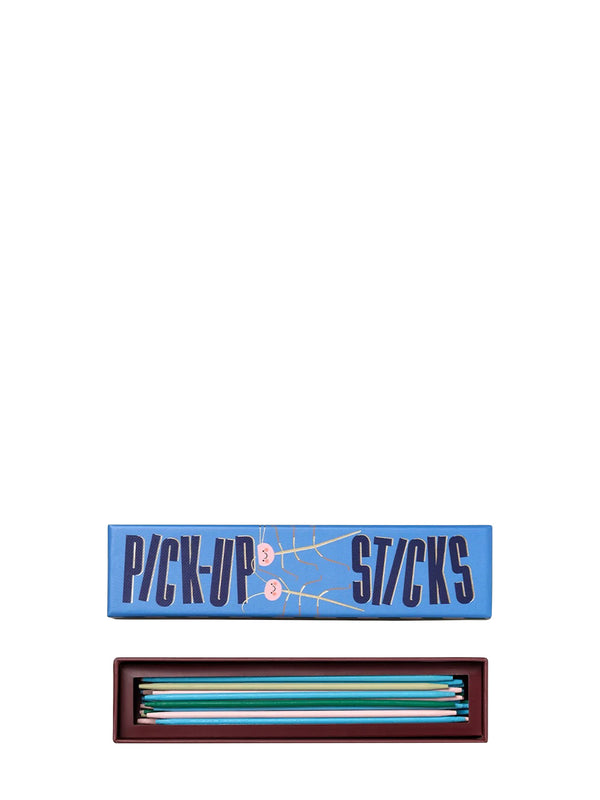 A boxed set of pick-up sticks game shown on a plain white background, with the blue lid labeled 'PICK-UP STICKS' above an open dark tray containing multiple colored sticks.