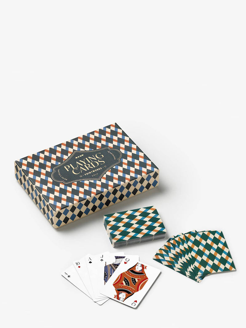 A boxed deck of patterned playing cards with several cards fanned out in front, shown on a clean light gray studio background. The box and card backs feature a repeating diamond/check pattern in teal, cream, and orange, with a dark central label reading 'Printworks', and at the lowest are 5 cards open in a fan shape with elegantly illustrated queen of hearts in ochre and equally stylish jack of clubs visible in blue and teal.