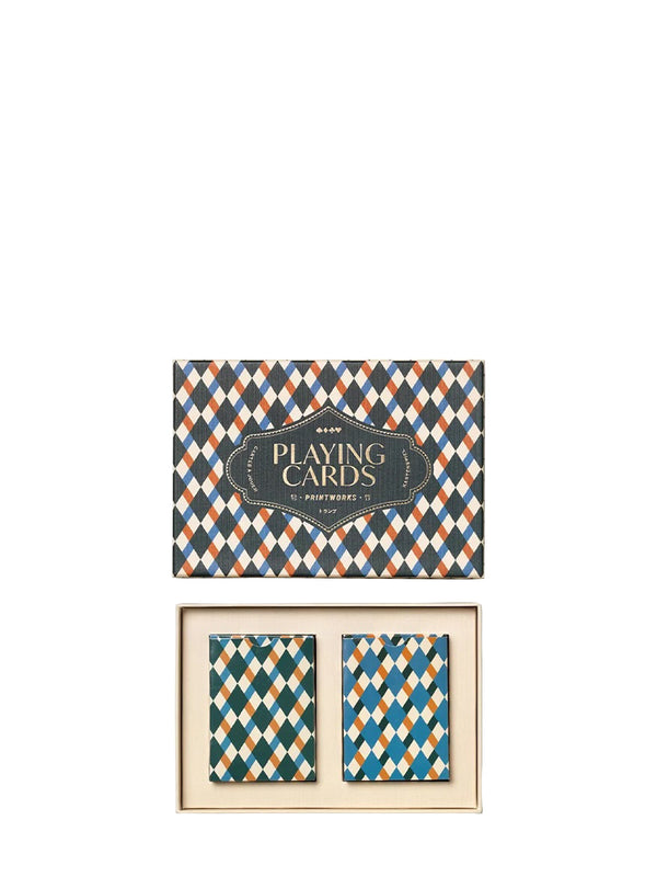 A boxed deck of patterned playing cards shown on a white background, with the closed box above and the open tray with two cards below. The cards and box feature an argyle-style diamond pattern in teal, navy, cream, and rust orange, with a dark central label reading 'PLAYING CARDS' and smaller text 'Printworks'.