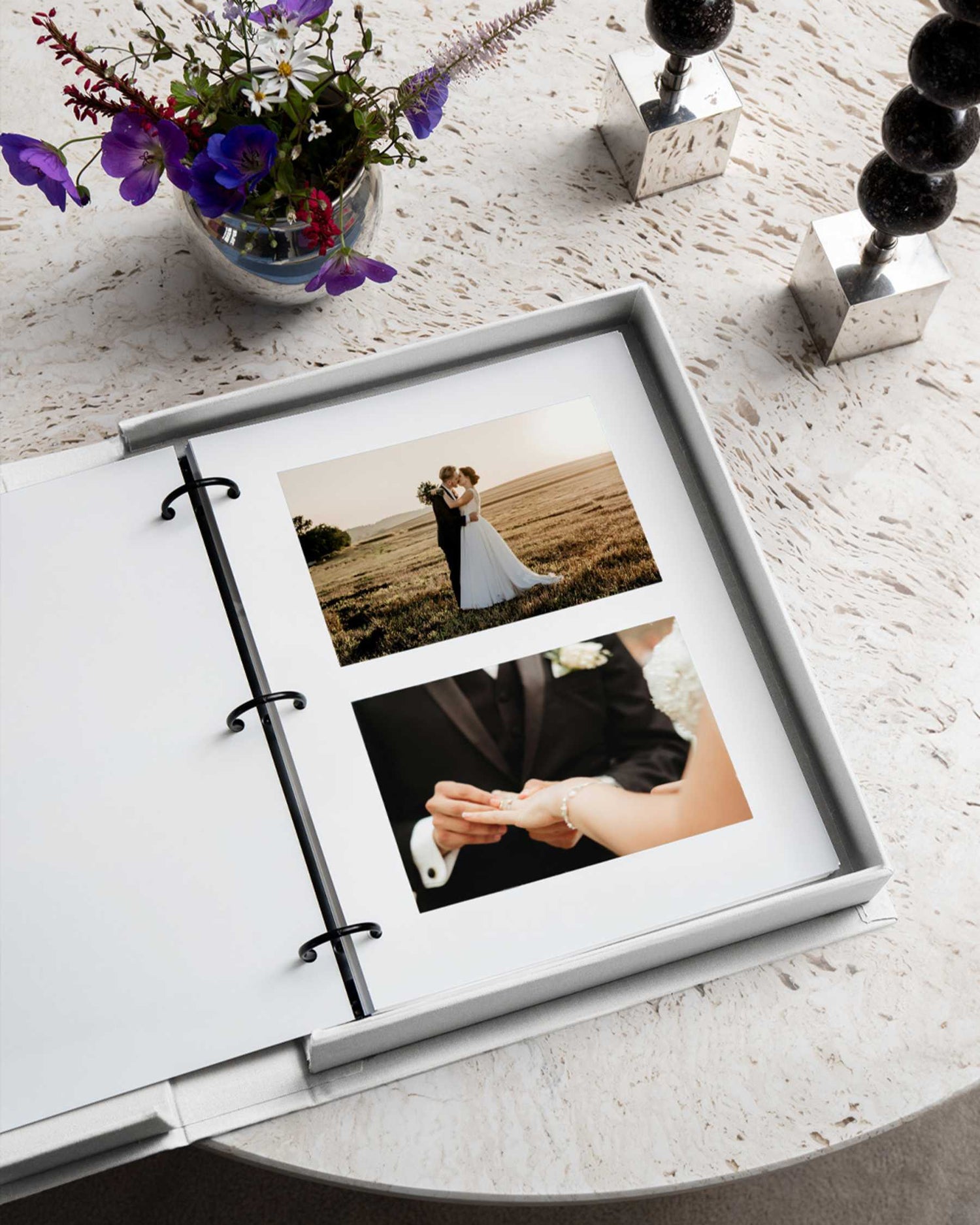 Open photo album with wedding photos on a light surface with flowers and decorative items.