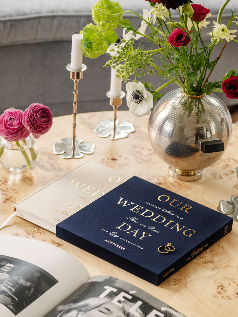 Decorative table setting with 'Our Wedding Day' book, flowers, and candles.