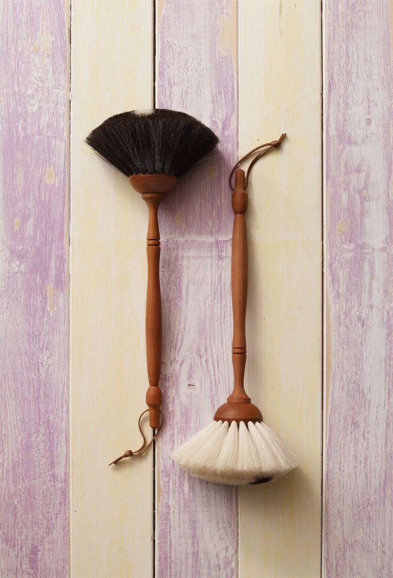 Two traditional cleaning brushes with wooden handles on a wooden background
