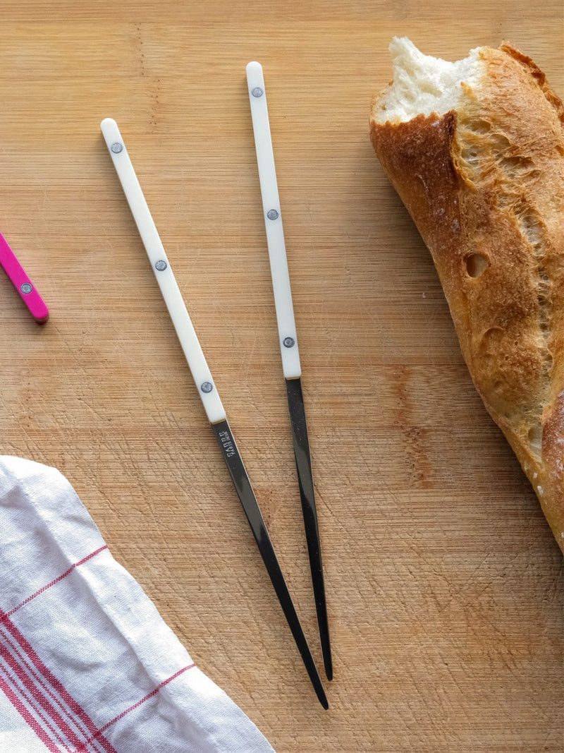 Two chopsticks on a wooden surface with a loaf of bread 