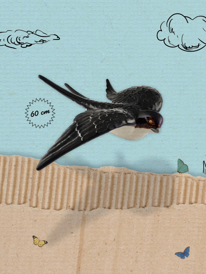 Ceramic swallow flying over a textured surface with a blue sky and clouds in the background