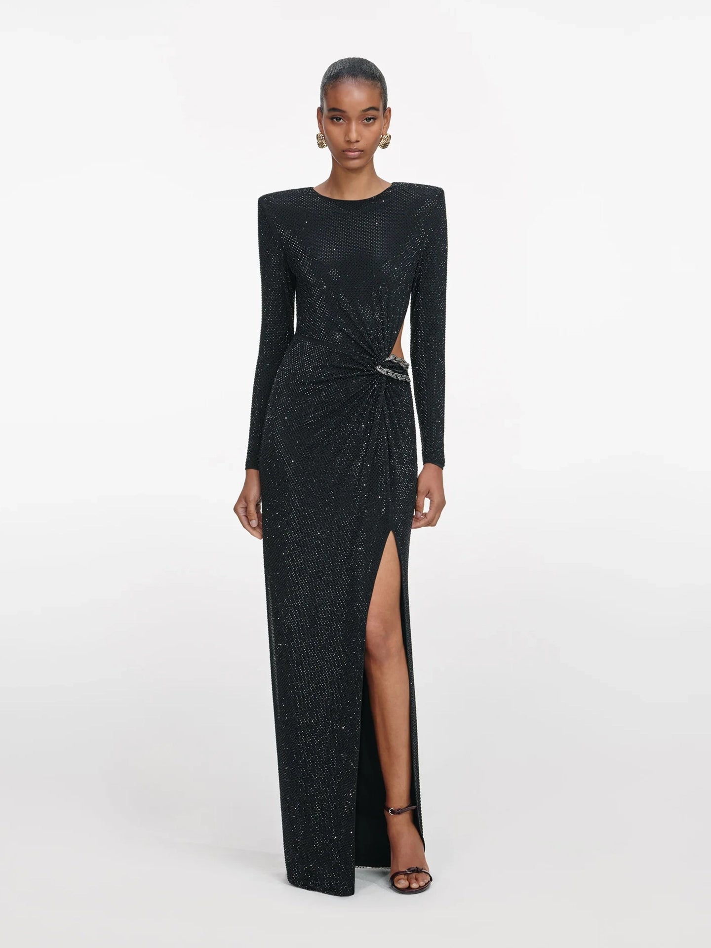Black evening gown with long sleeves and a slit on a white background