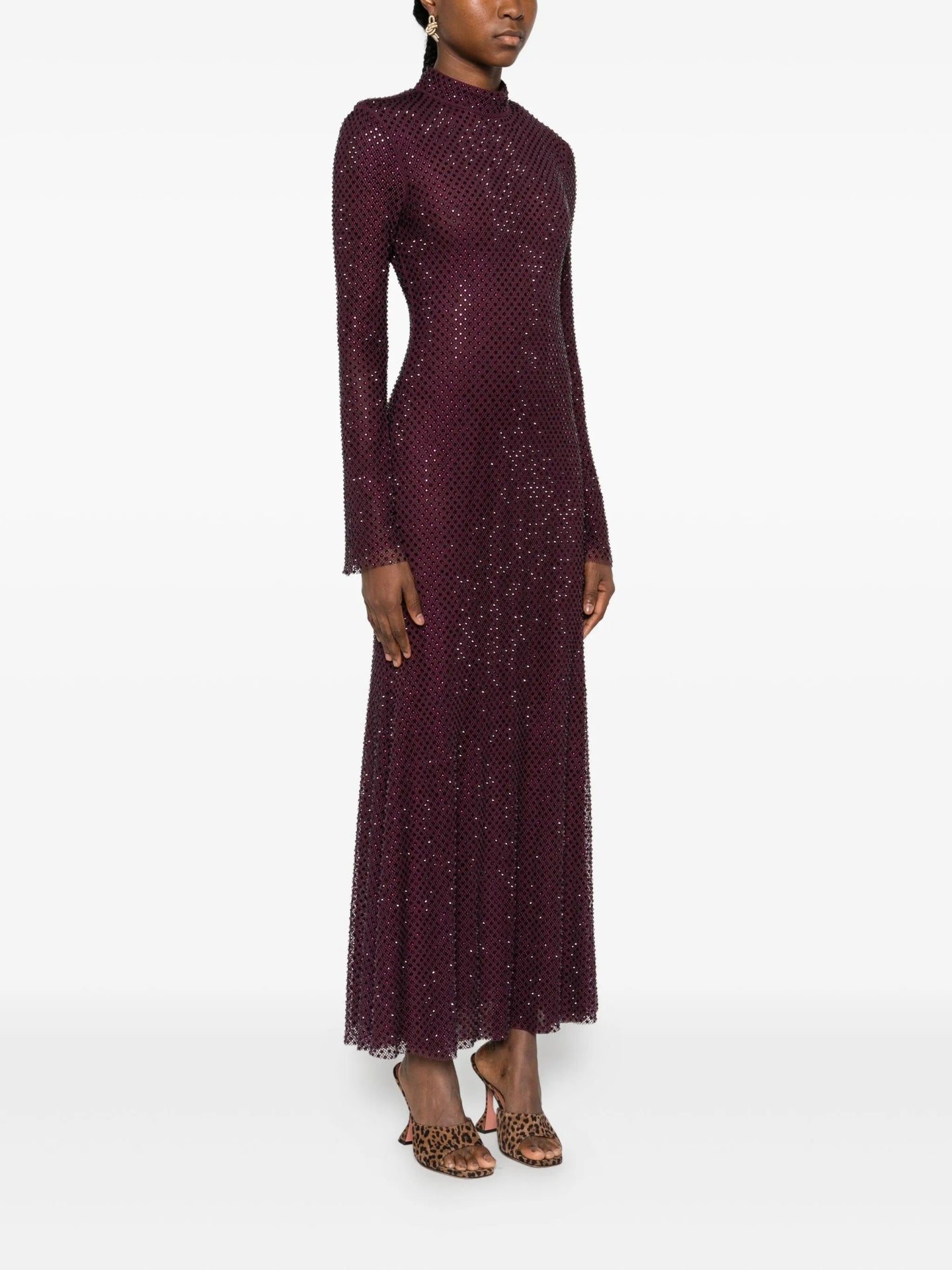Woman wearing a long burgundy dress with a pattern on a white background