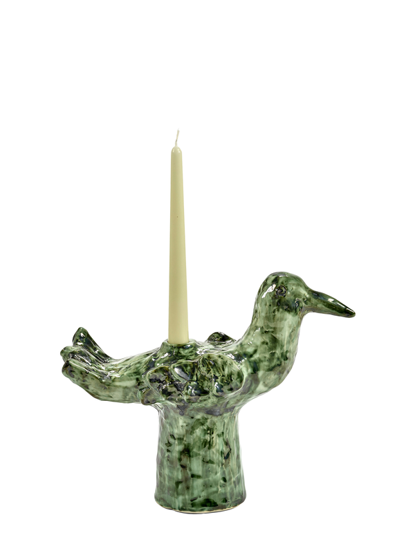 A green ceramic candle holder in the shape of a bird with a candle placed on its back.