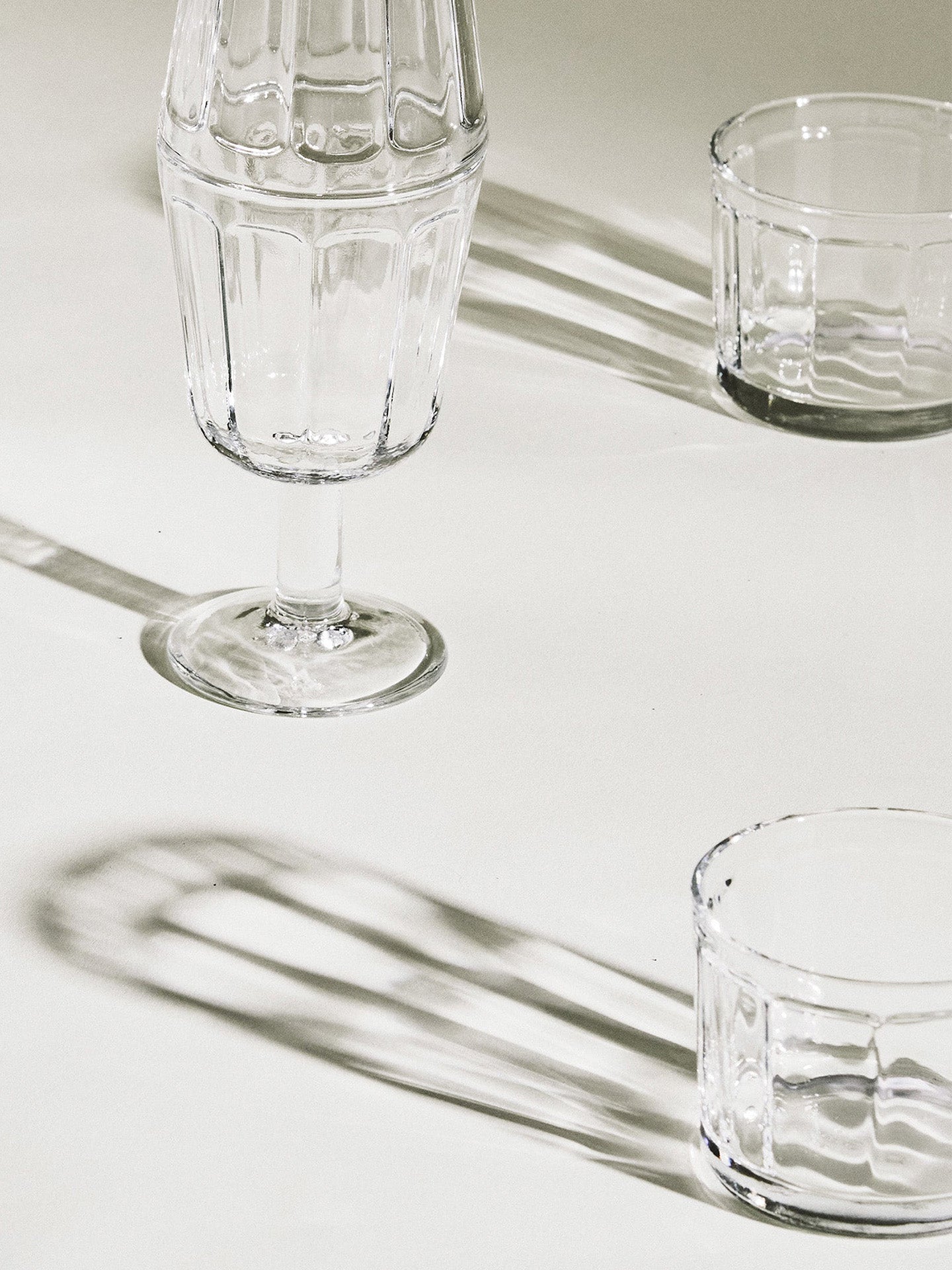 Clear glassware on a light surface reflecting sunlight
