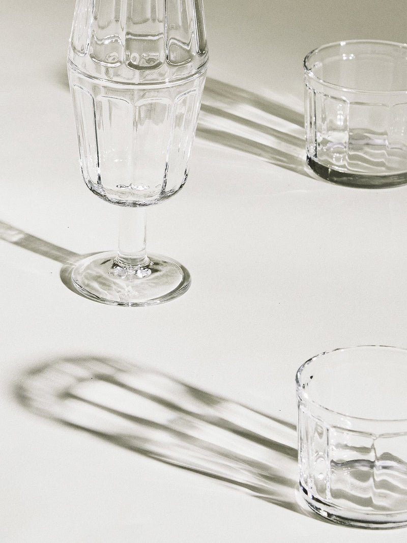 Clear glassware on a light surface reflecting sunlight